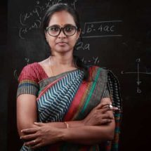 Portrait of an Indian lady teacher stands in front of a blackboard
